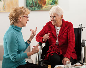 Caregiver connecting with her client over tea and cake